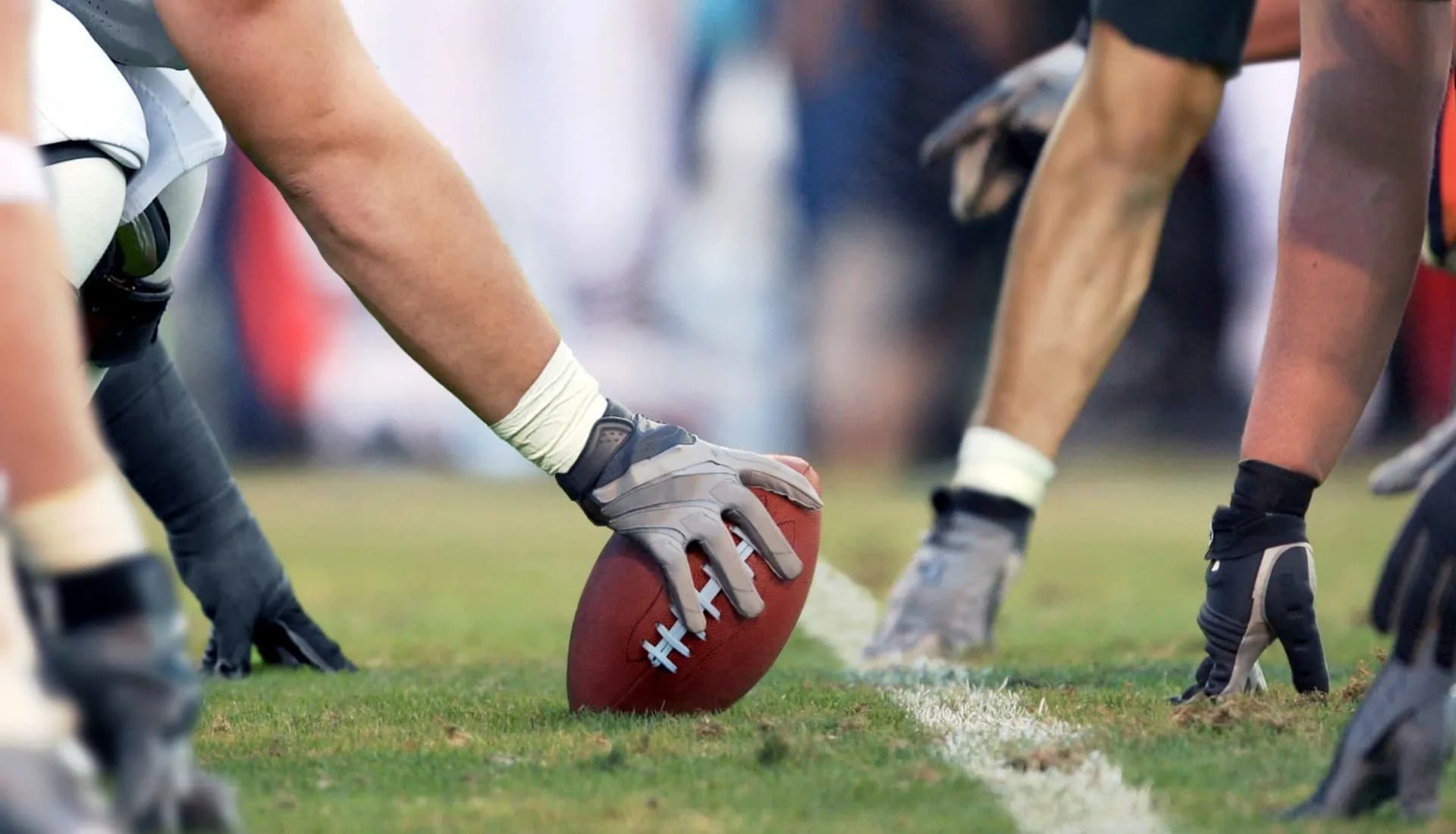 A close-up of a football being prepared for a snap on the field. A close-up of a football being prepared for a snap on the field.