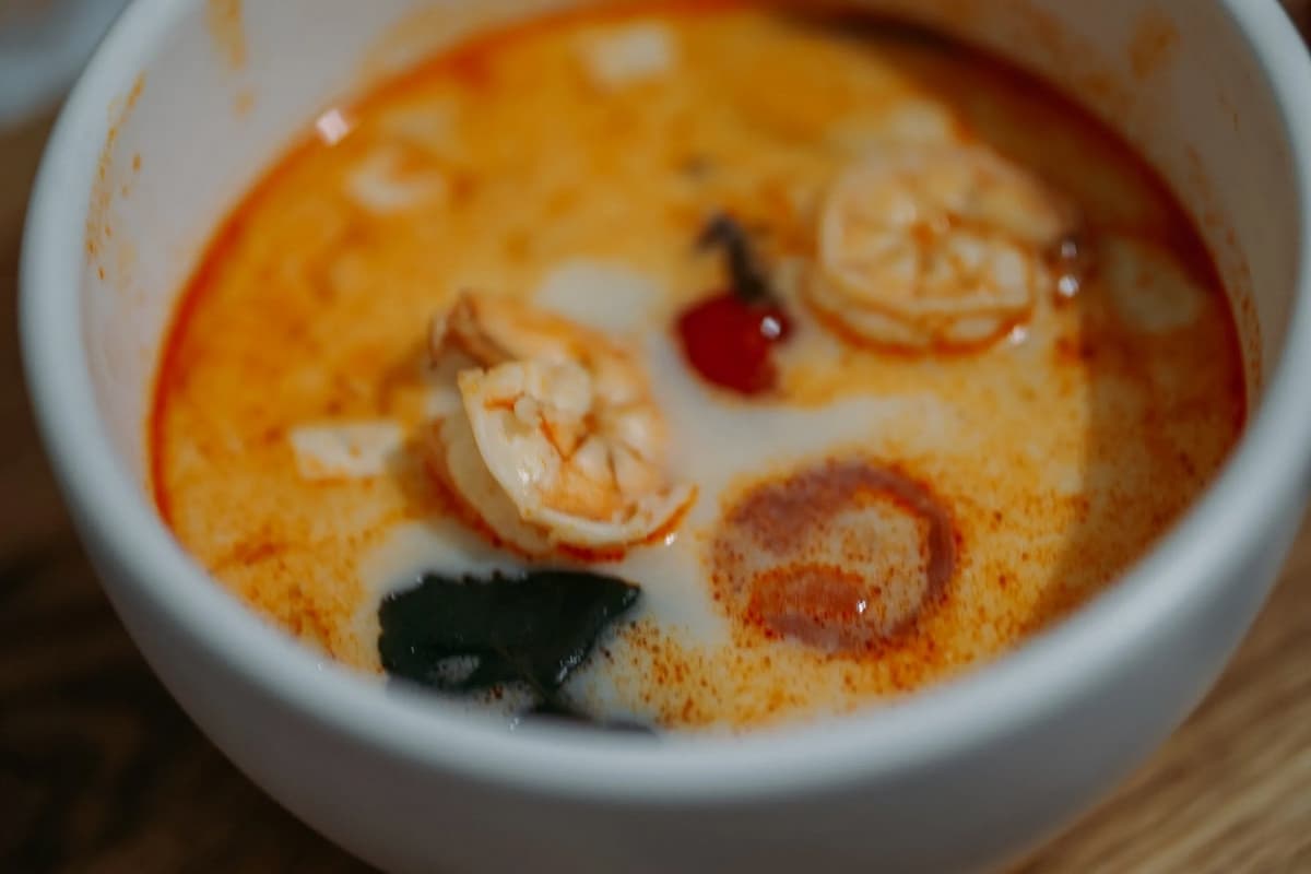 A bowl of shrimp soup with coconut milk, herbs, and spices.