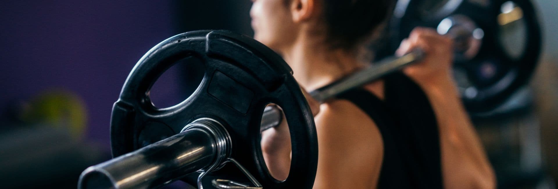 A person lifting a barbell in a gym setting.