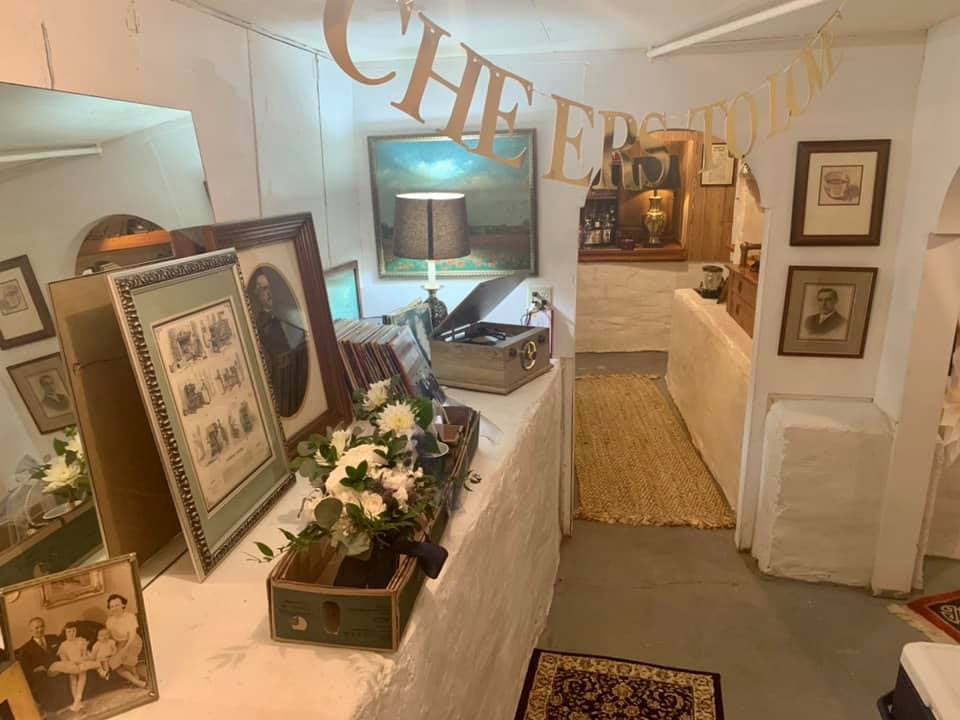 A cozy, vintage hallway adorned with framed photos, a lamp, and a decorative "CHEERS" banner.