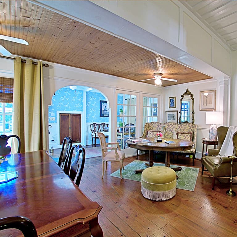A cozy, eclectic living space featuring a dining table, decorative armchairs, and a round coffee table.