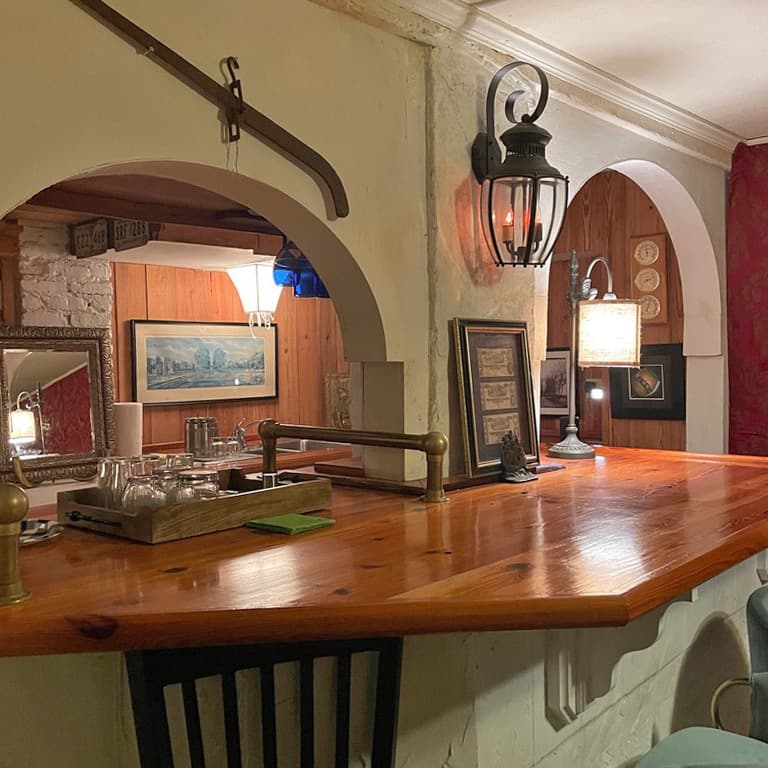 A cozy interior of a bar featuring wooden furniture, vintage decor, and warm lighting.