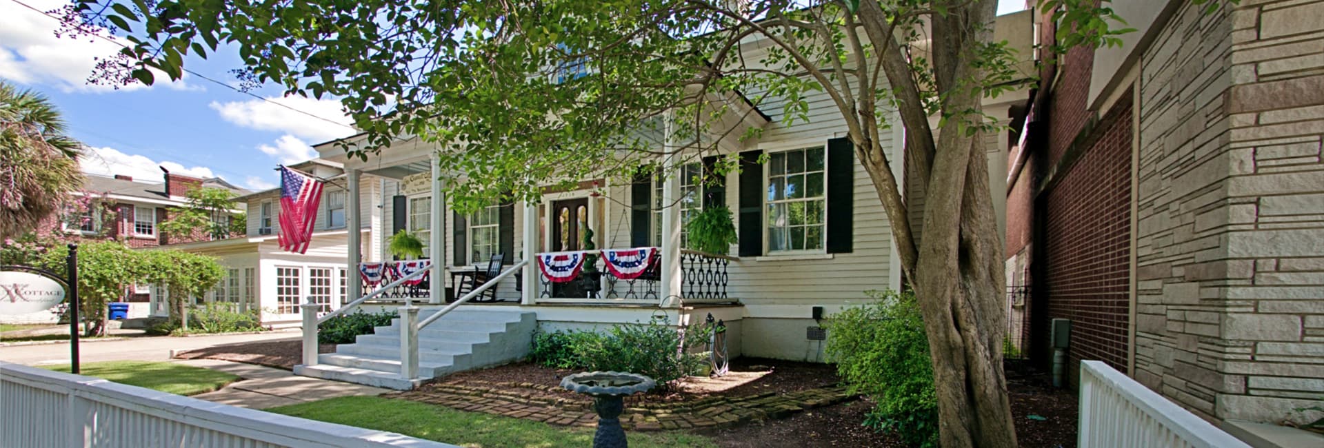 A charming house adorned with patriotic decorations and surrounded by greenery.