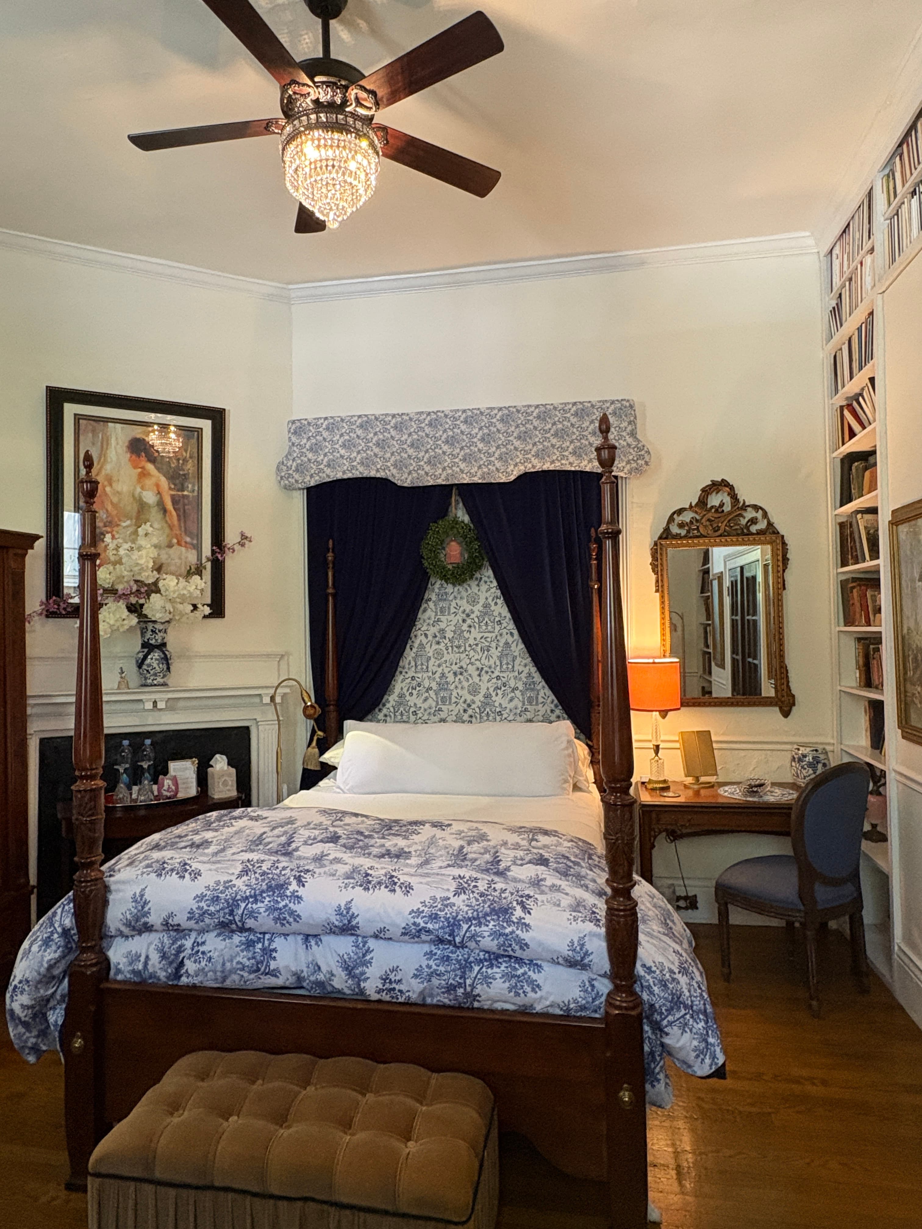 A cozy bedroom featuring a four-poster bed, a desk, and decorative elements in soft colors.
