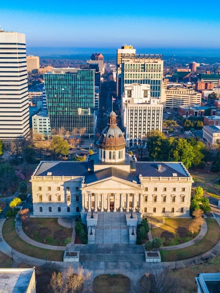 Aerial view of a historic government building surrounded by modern skyscrapers.