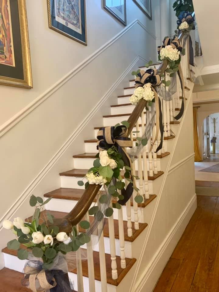 A decorated staircase with floral arrangements and ribbons.