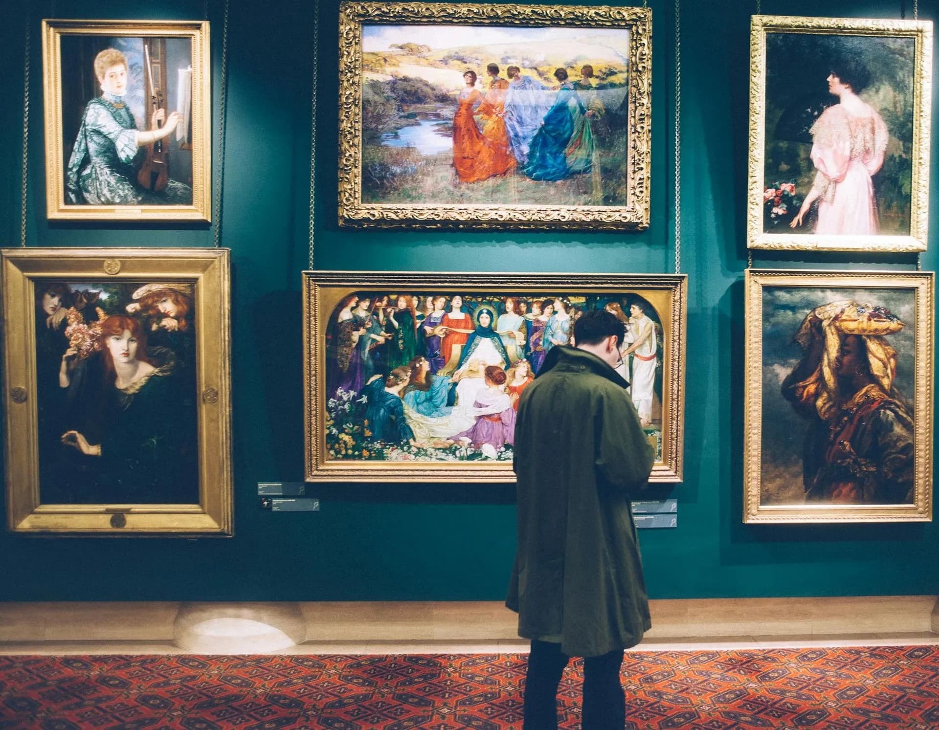 A visitor admires a collection of classic paintings in a dimly lit gallery. A visitor admires a collection of classic paintings in a dimly lit gallery.
