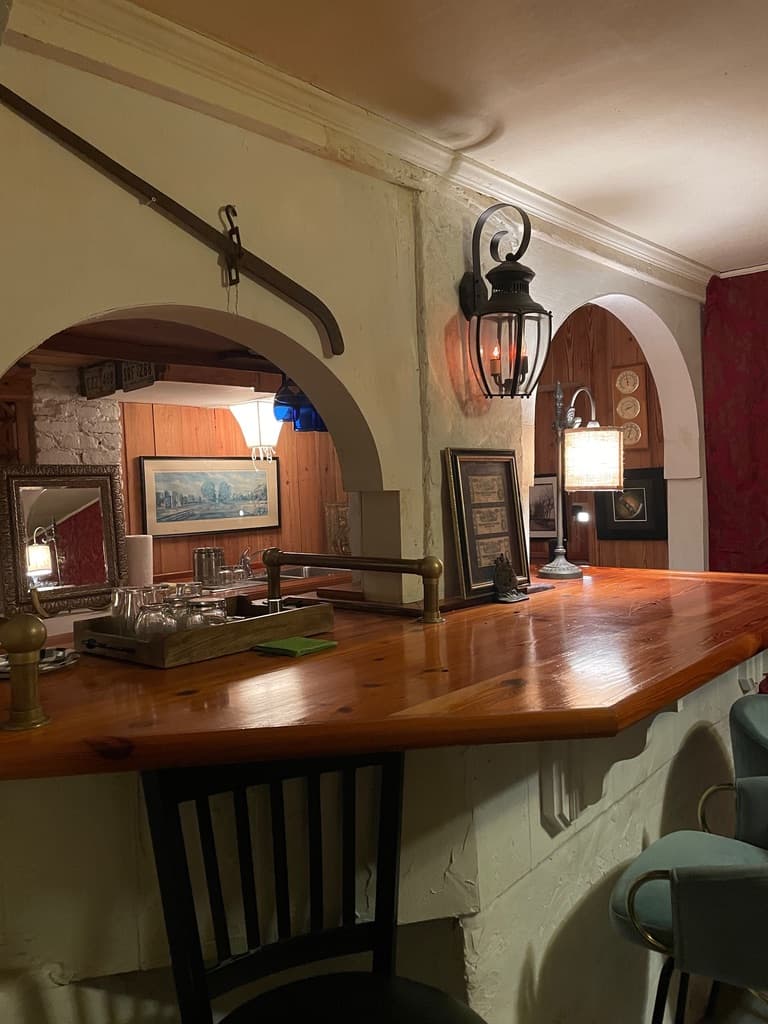 A wooden bar with decorative lanterns and framed artwork in a cozy, dimly lit room.