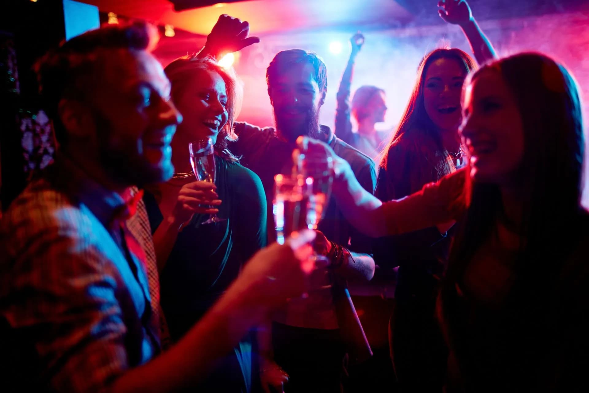 A group of cheerful friends celebrates together in a vibrant, colorful nightlife scene. A group of cheerful friends celebrates together in a vibrant, colorful nightlife scene.