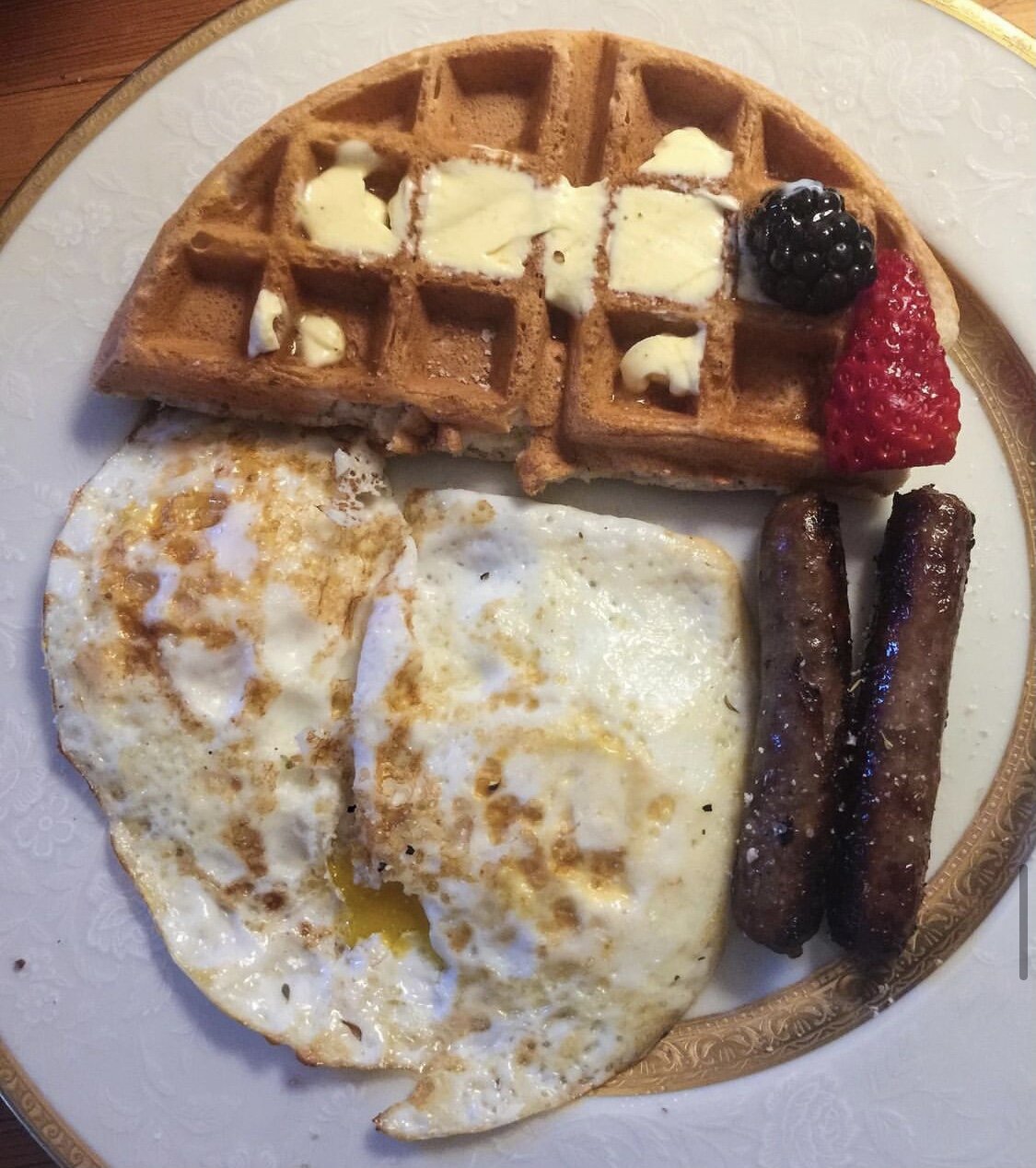 Waffle, eggs over medium, sausage, and some fresh fruit